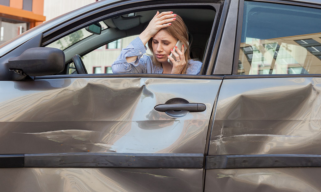 Young woman holding head after car accident