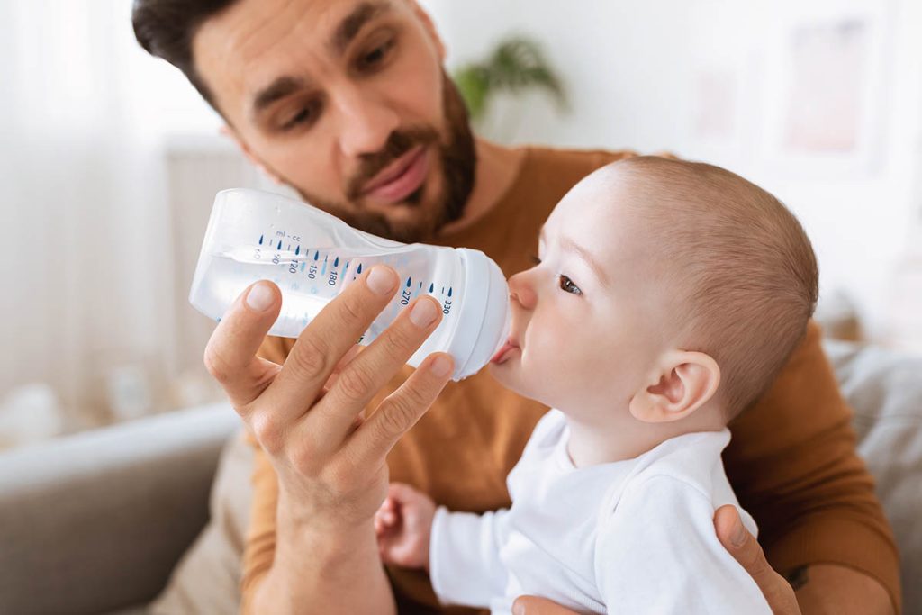 Man on paternity leave giving his child water