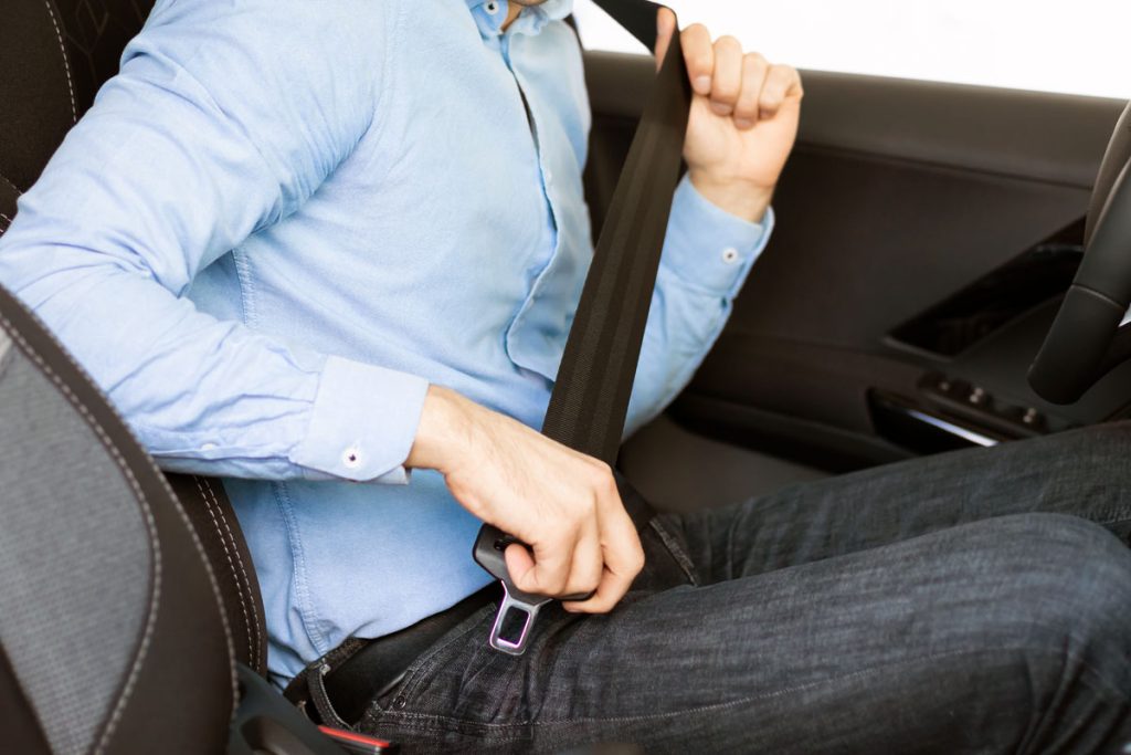 driver putting on seatbelt in a car for safety